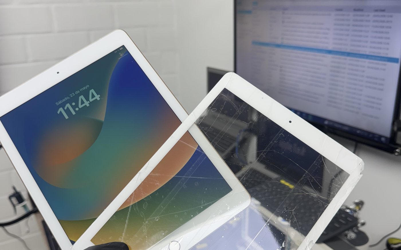 Un iPad con el táctil trizado junto a otro ya reparado, sobre la mesa de trabajo